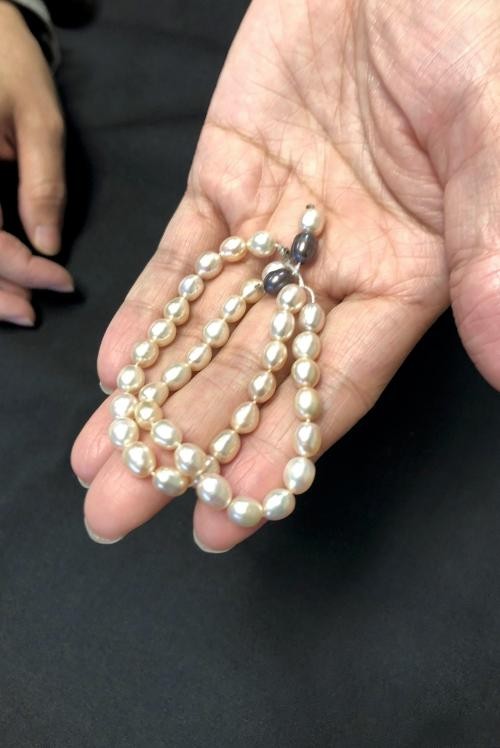 Eine Hand zeigt ein Armkettchen aus Perlen. 