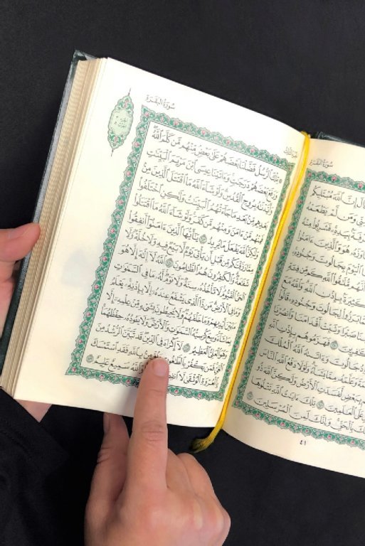 Eine Frau zeigt auf eine Sure im Koran